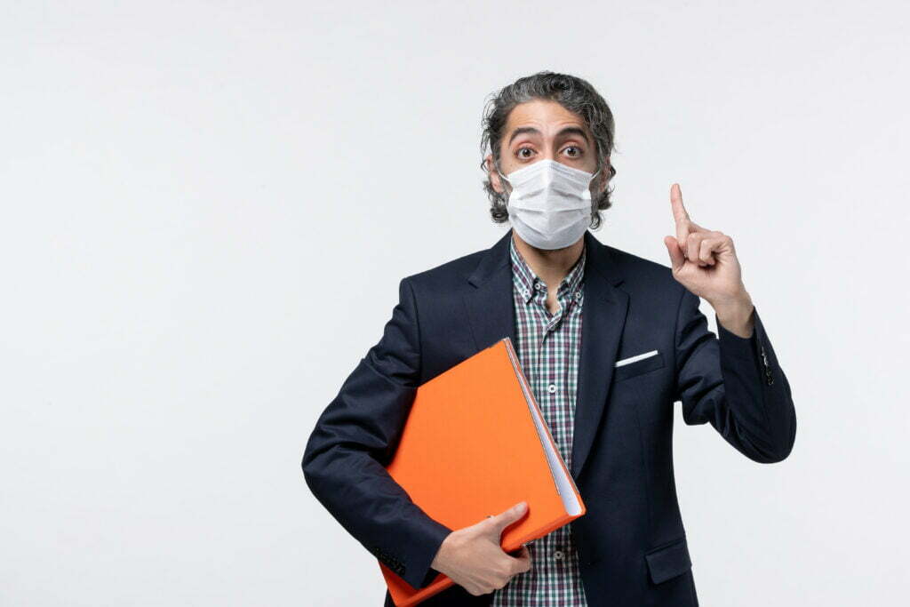 business guy suit holding his documents wearing surgical mask pointing up white surface